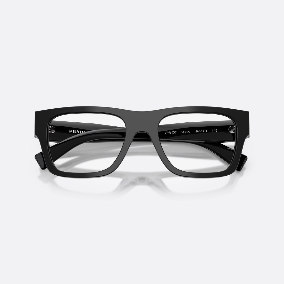 Prada PR C01V 16K1O1 eyeglasses, black pillow frame for men, plain saddle bridge, brand lettering on temples, folded